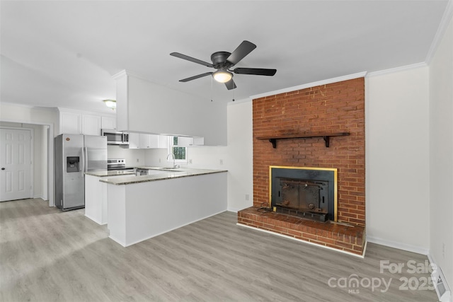 kitchen with ornamental molding, a sink, white cabinetry, appliances with stainless steel finishes, and light wood finished floors