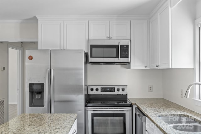 kitchen with a sink, light stone countertops, appliances with stainless steel finishes, and white cabinetry