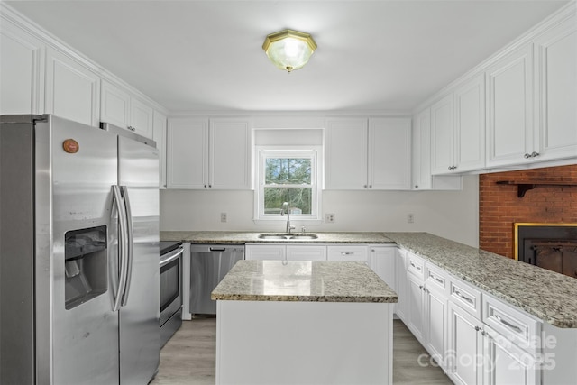 kitchen with light stone countertops, a sink, stainless steel appliances, white cabinetry, and light wood-type flooring