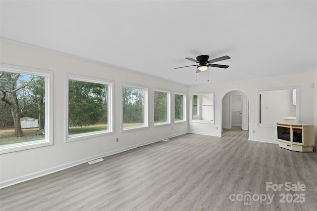 interior space featuring arched walkways, visible vents, a ceiling fan, and a wealth of natural light