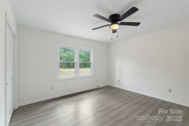 unfurnished bedroom with ceiling fan, visible vents, baseboards, and wood finished floors