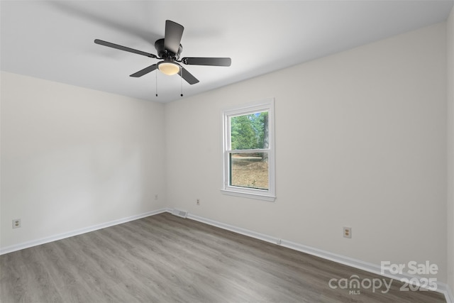 empty room with visible vents, baseboards, wood finished floors, and a ceiling fan