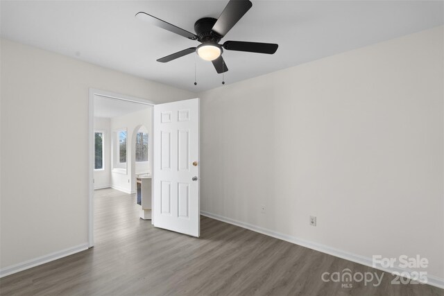 spare room with a ceiling fan, baseboards, and wood finished floors