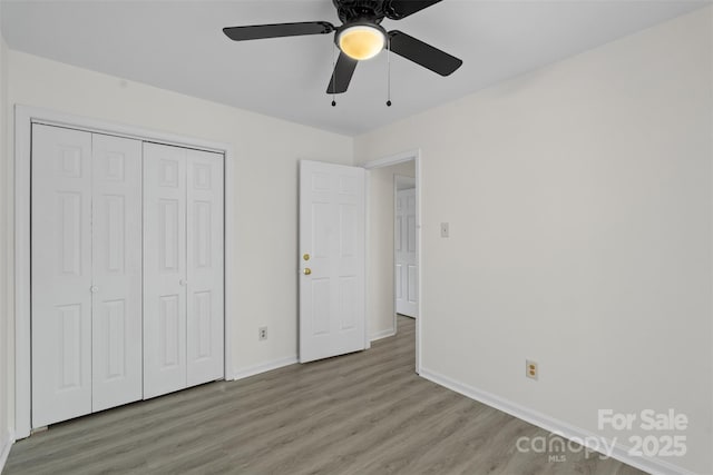 unfurnished bedroom with light wood-type flooring, baseboards, a closet, and ceiling fan