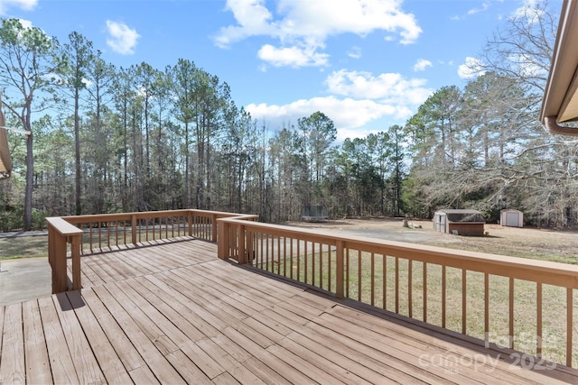 wooden deck featuring a yard, an outdoor structure, and a shed