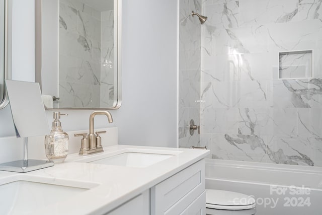 full bathroom featuring tiled shower / bath, vanity, and toilet