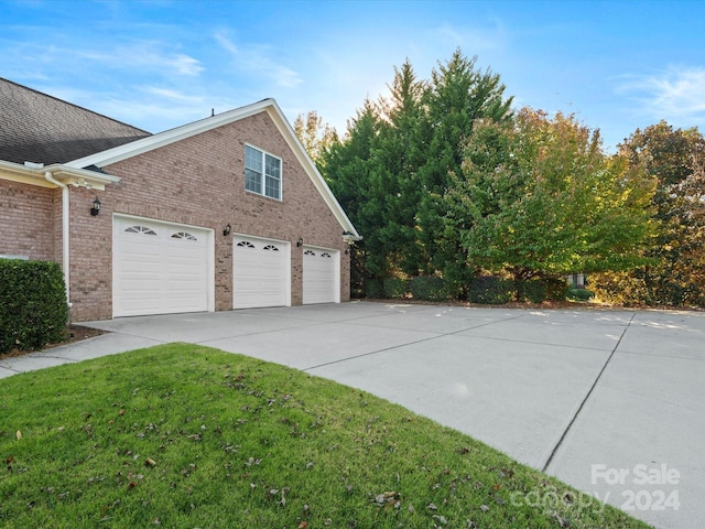 view of side of home featuring a garage and a lawn