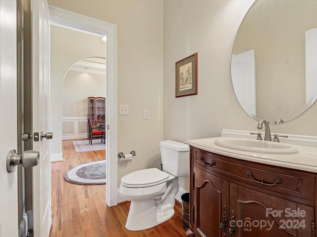 bathroom with toilet, crown molding, vanity, and wood-type flooring