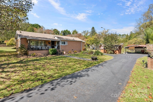 ranch-style house with a front yard, covered porch, and a carport