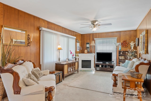 carpeted living room featuring wooden walls and ceiling fan