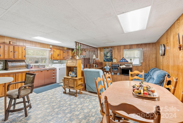 dining room with wooden walls, a paneled ceiling, sink, and washer / clothes dryer