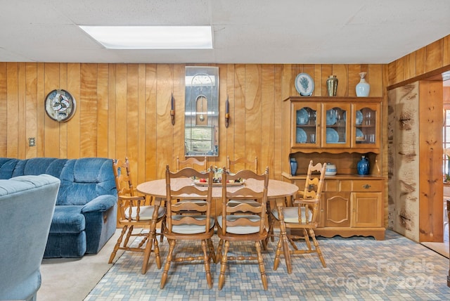 carpeted dining room with wood walls