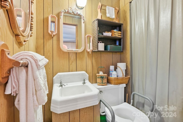 bathroom featuring wood walls, sink, and toilet