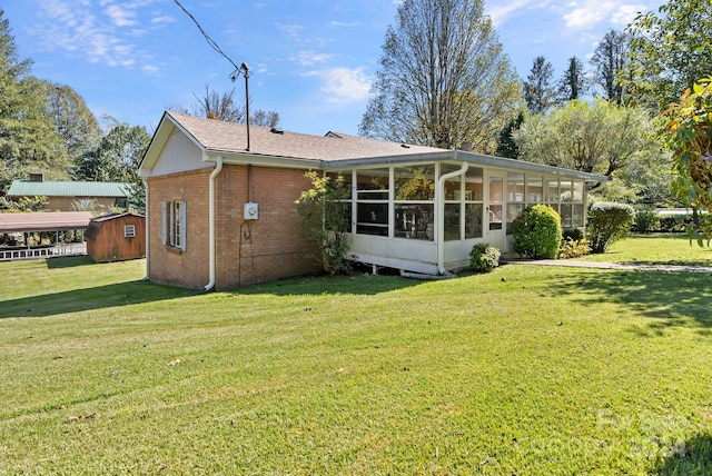 back of house with a yard, a sunroom, and a shed