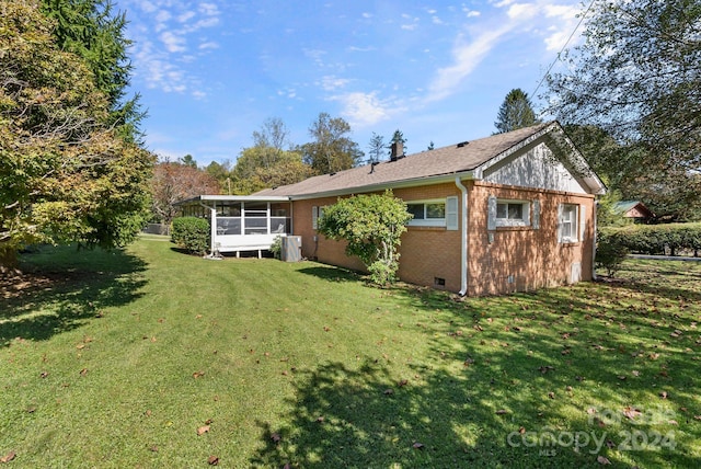 rear view of house featuring a yard and a sunroom