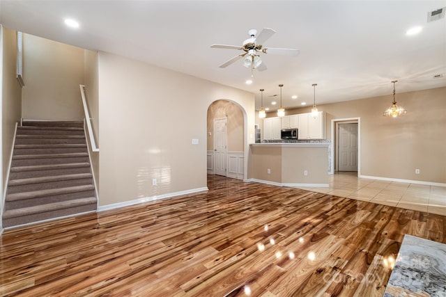 unfurnished living room with light hardwood / wood-style flooring and ceiling fan with notable chandelier