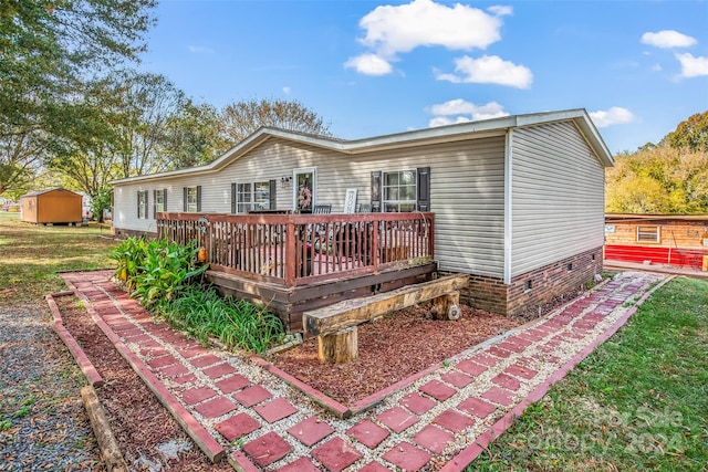 back of house with a storage shed and a wooden deck