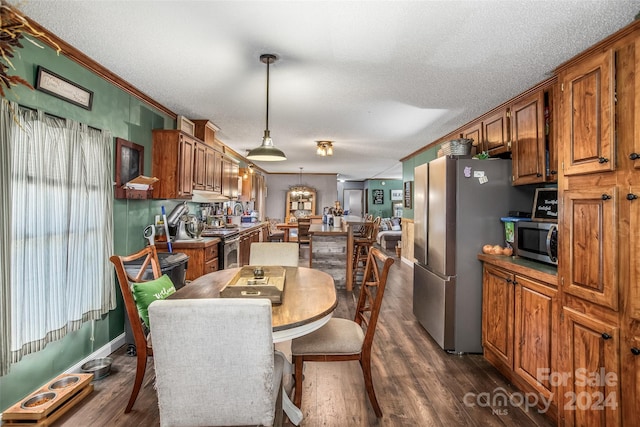 kitchen with a textured ceiling, ornamental molding, dark hardwood / wood-style floors, stainless steel appliances, and decorative light fixtures