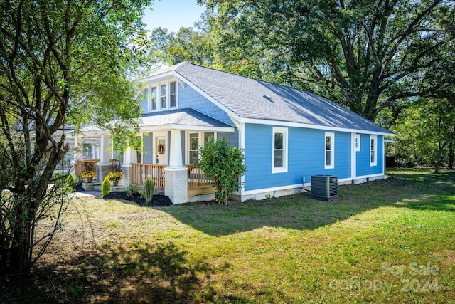 rear view of house featuring a porch, a yard, and cooling unit