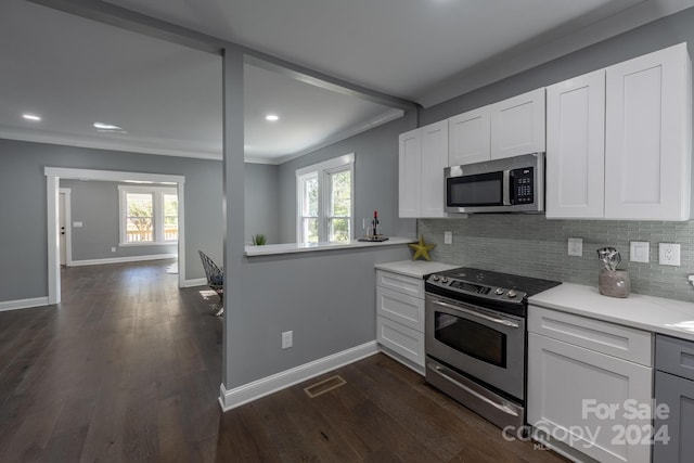 kitchen with appliances with stainless steel finishes, plenty of natural light, white cabinetry, and dark hardwood / wood-style floors