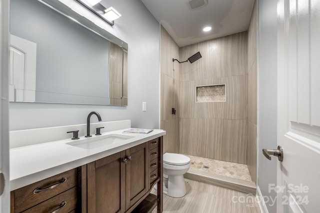 bathroom featuring vanity, toilet, and tiled shower