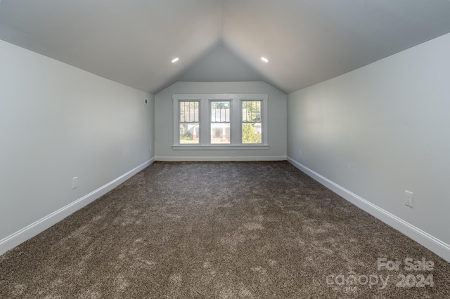 carpeted empty room featuring lofted ceiling