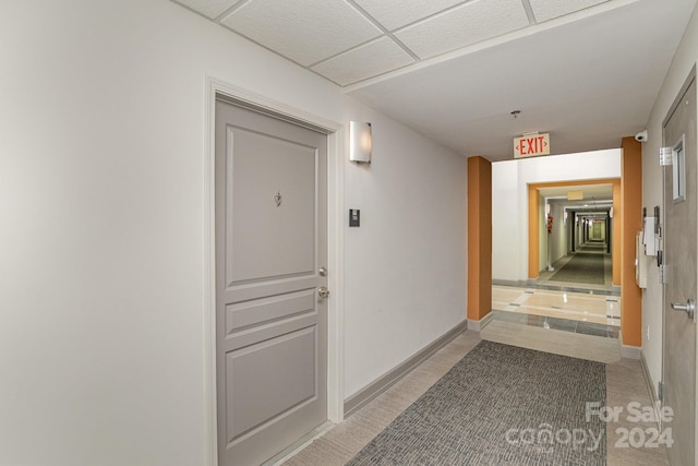 hall featuring a paneled ceiling and light tile patterned floors