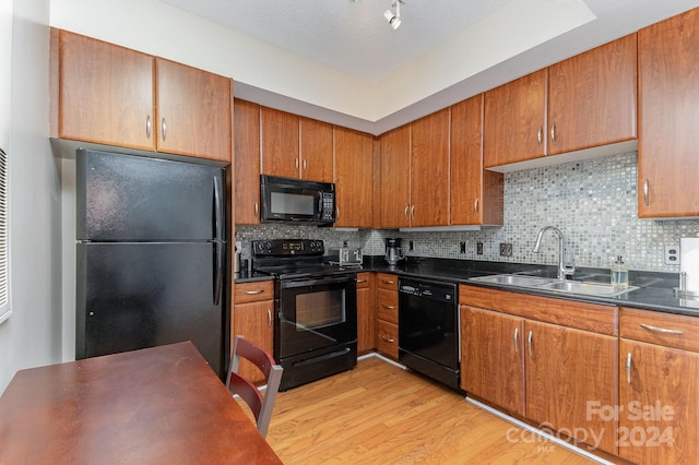 kitchen featuring black appliances, light wood-type flooring, sink, and tasteful backsplash