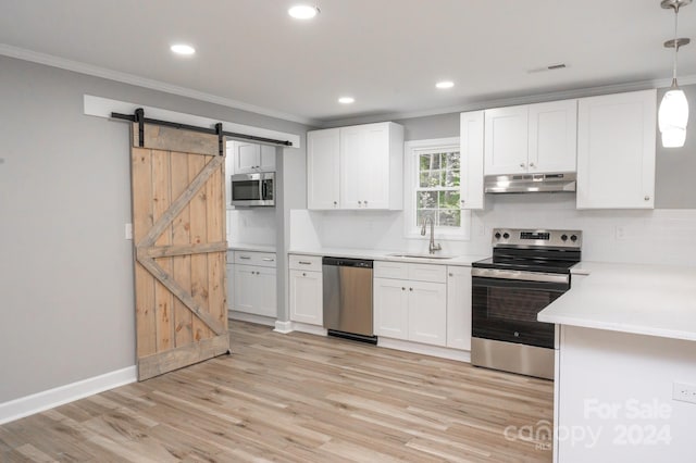 kitchen with white cabinets, hanging light fixtures, appliances with stainless steel finishes, a barn door, and sink