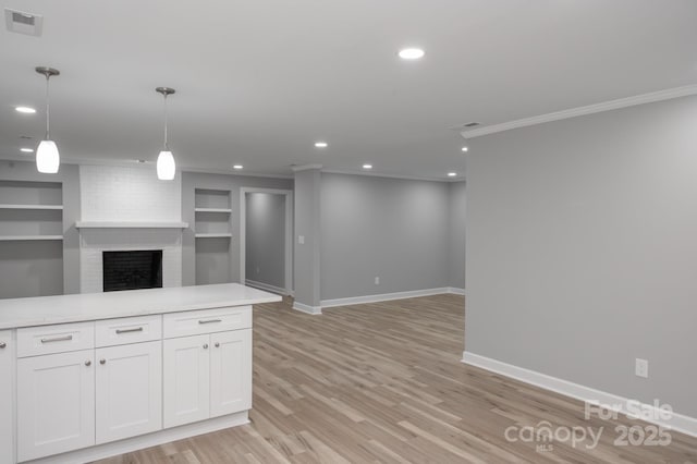 kitchen featuring crown molding, light hardwood / wood-style flooring, built in features, white cabinetry, and decorative light fixtures