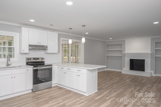 kitchen featuring electric stove, sink, pendant lighting, and kitchen peninsula