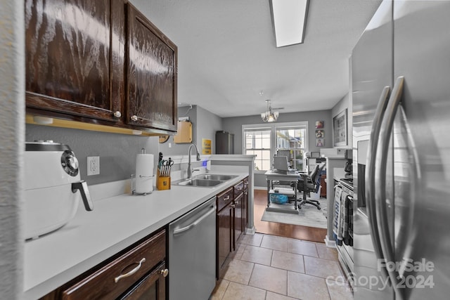 kitchen with light hardwood / wood-style floors, dark brown cabinets, stainless steel appliances, and sink