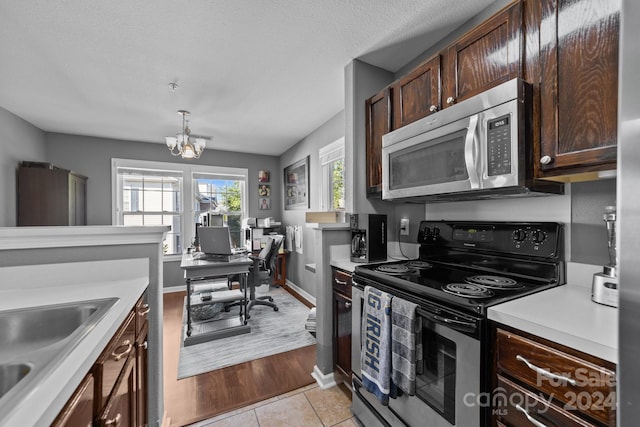 kitchen featuring dark brown cabinets, sink, a chandelier, appliances with stainless steel finishes, and light hardwood / wood-style floors