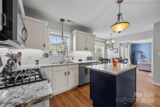 kitchen with a kitchen island, white cabinetry, light hardwood / wood-style flooring, sink, and stainless steel appliances