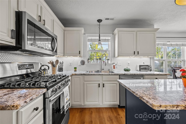 kitchen featuring white cabinetry, stainless steel appliances, sink, and light wood-type flooring