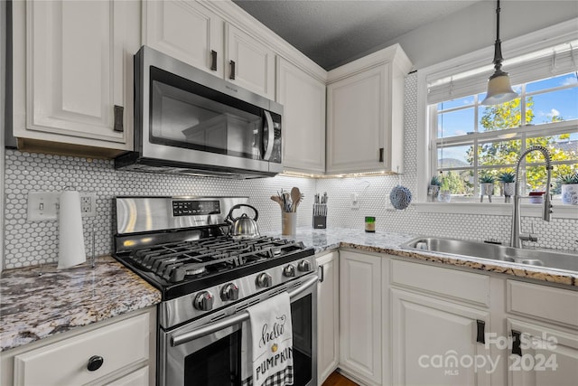 kitchen featuring tasteful backsplash, sink, a textured ceiling, white cabinetry, and stainless steel appliances