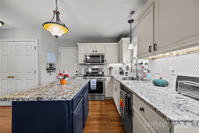 kitchen featuring white cabinets, stainless steel appliances, sink, and a kitchen island