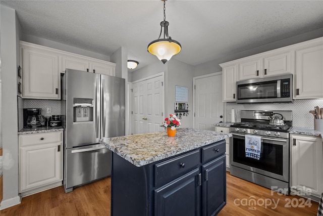 kitchen featuring appliances with stainless steel finishes, white cabinets, hardwood / wood-style flooring, and a center island