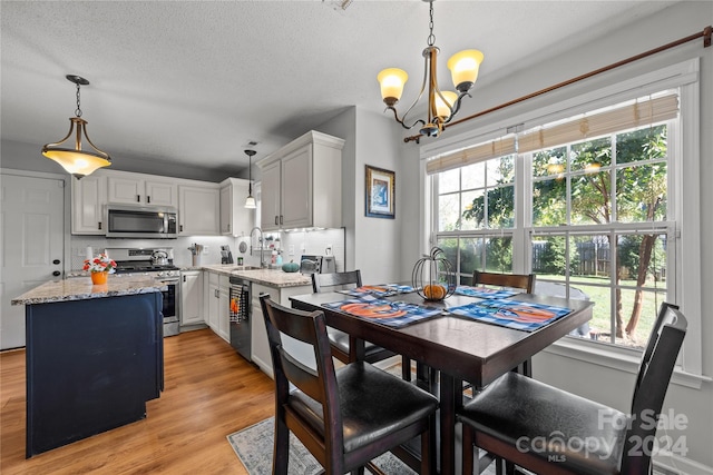 dining area with light hardwood / wood-style floors, a chandelier, sink, and a wealth of natural light