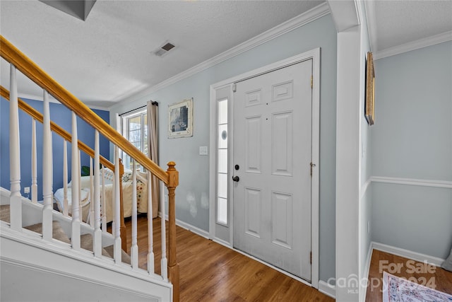 foyer entrance featuring crown molding, hardwood / wood-style flooring, and a textured ceiling