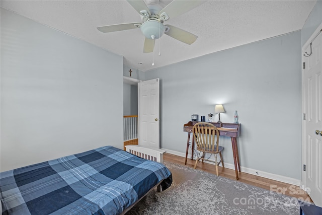 bedroom featuring a textured ceiling, wood-type flooring, and ceiling fan