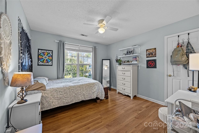 bedroom with hardwood / wood-style floors, a textured ceiling, and ceiling fan