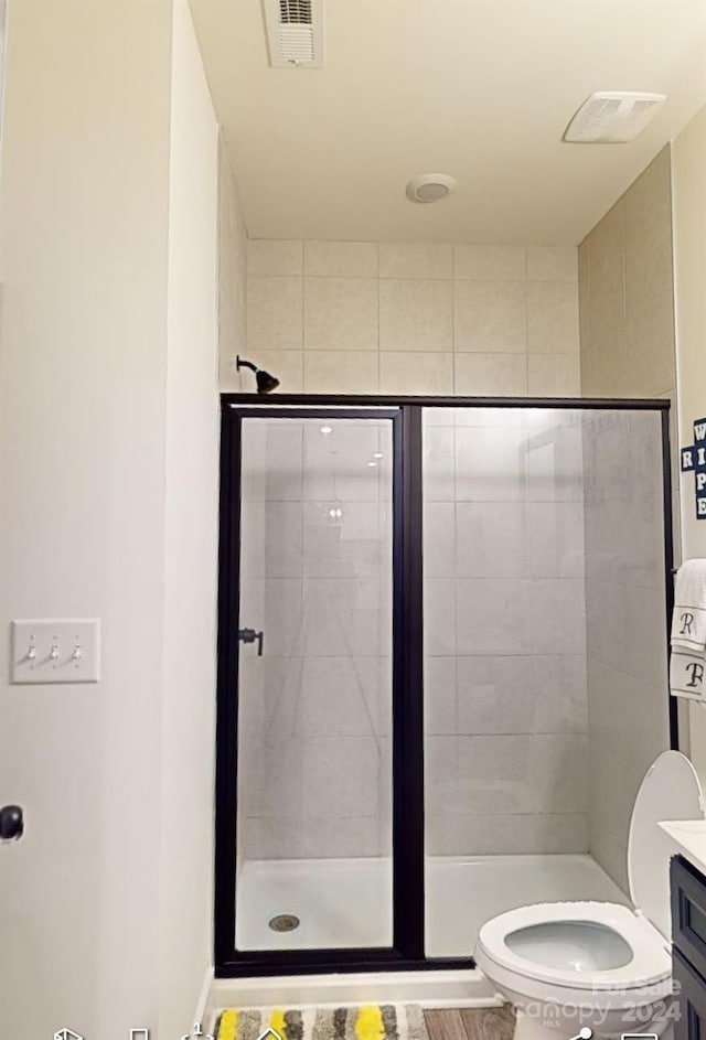 bathroom with vanity, a shower with shower door, and toilet