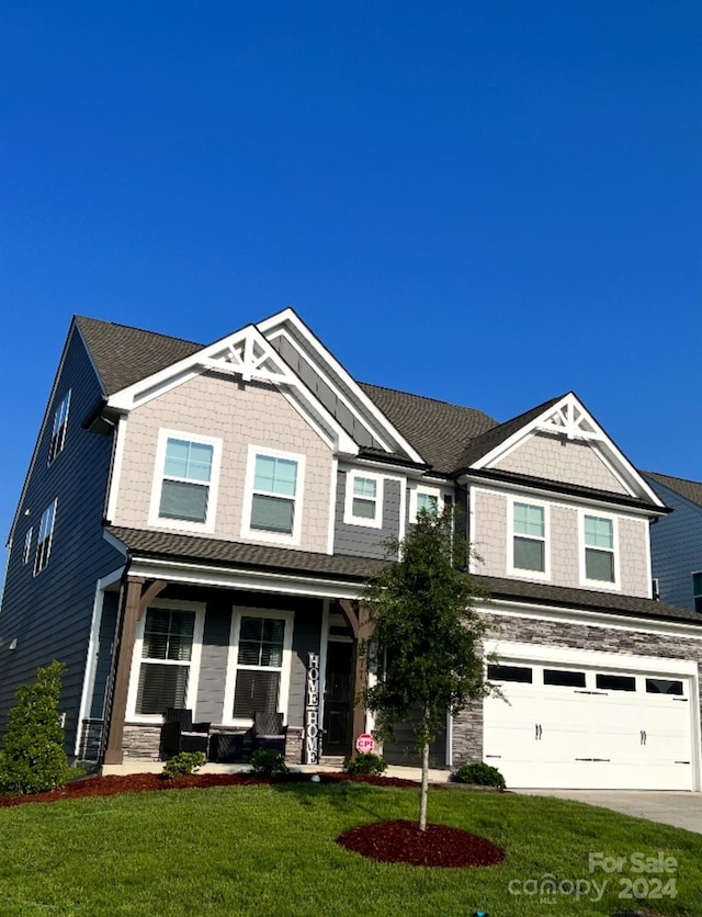 craftsman house with covered porch, a front yard, and a garage