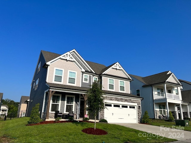 craftsman inspired home featuring a balcony, covered porch, a garage, and a front lawn