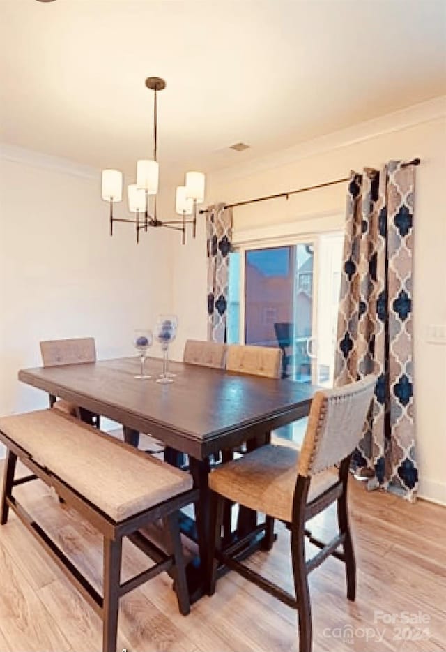 dining room featuring ornamental molding, light hardwood / wood-style flooring, and a notable chandelier