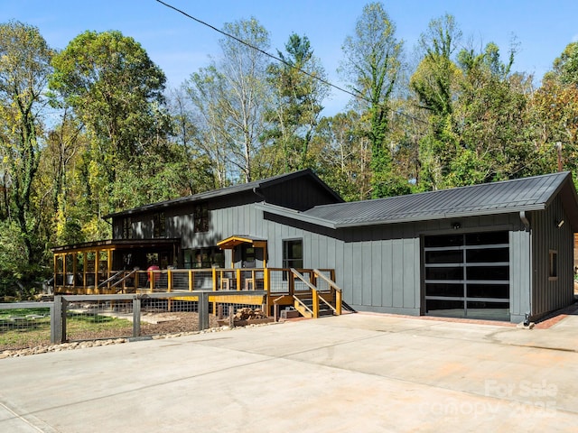 view of front of property with an attached garage, a standing seam roof, metal roof, and concrete driveway