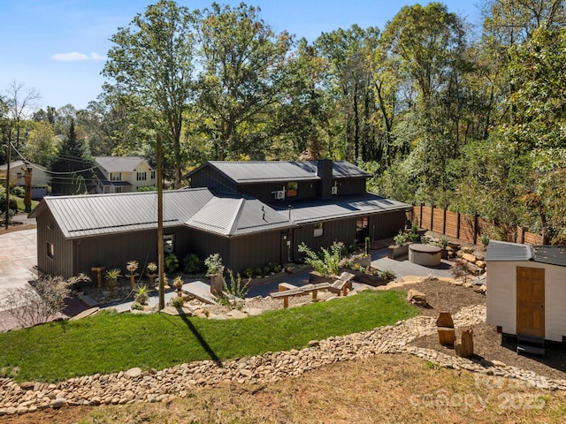 back of house featuring fence, a storage shed, board and batten siding, an outdoor structure, and metal roof