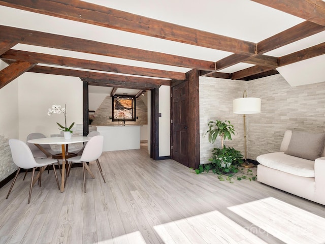 dining space featuring beam ceiling and wood finished floors