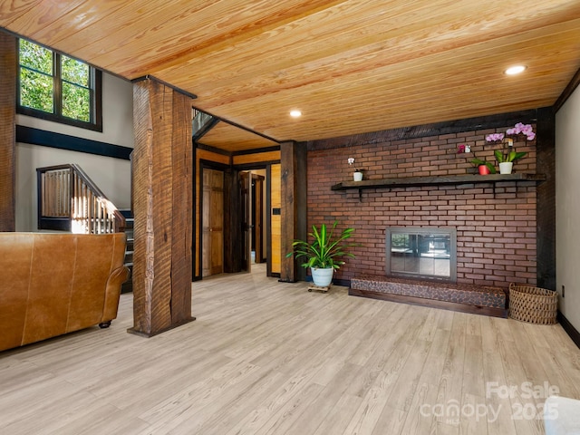 unfurnished living room with wood finished floors, recessed lighting, wooden ceiling, a brick fireplace, and stairs